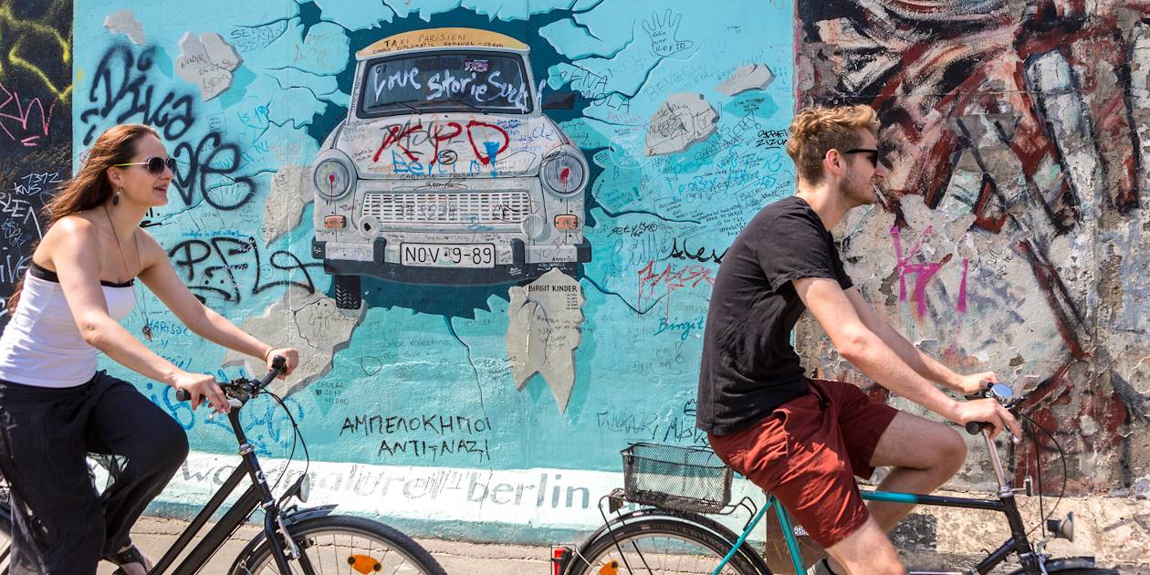 Cyclistes devant le mur de Berlin dans le quartier de Friedrichshain - Allemagne