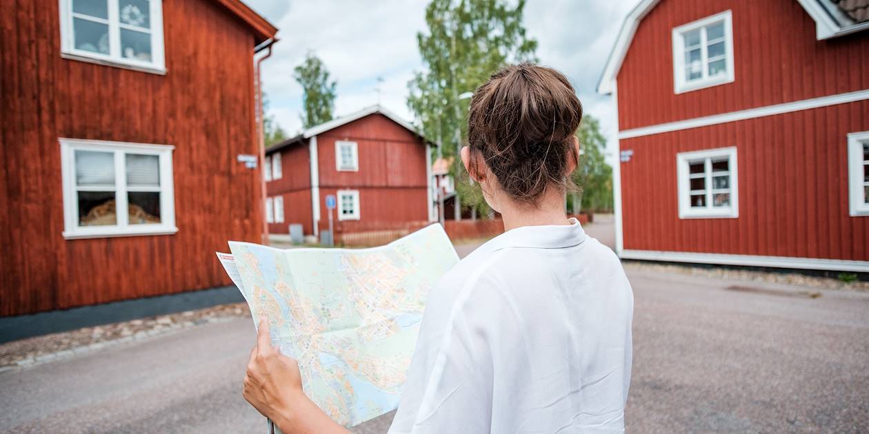 Femme se repérant dans le quartier des maisons en bois rouge de Falun - Comté de Dalécarlie - Suède