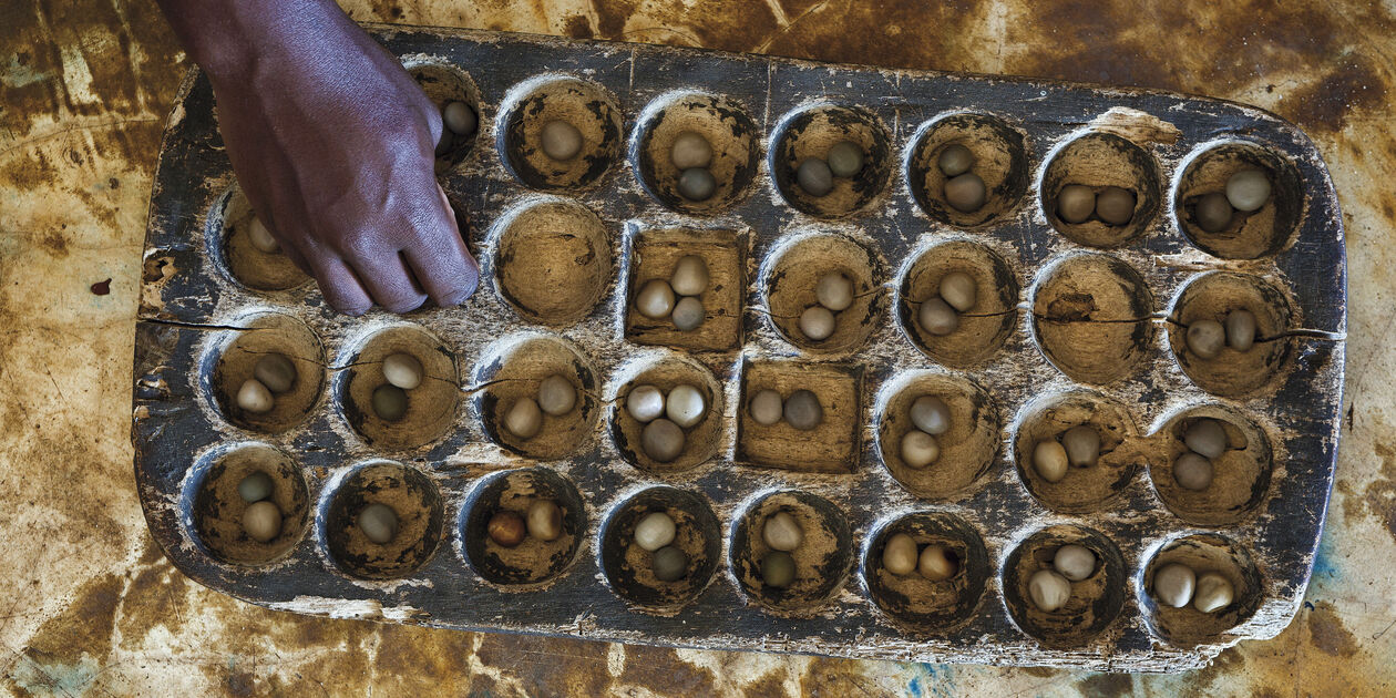 Homme jouant à l'Awale, jeu africain - Zanzibar - Tanzanie