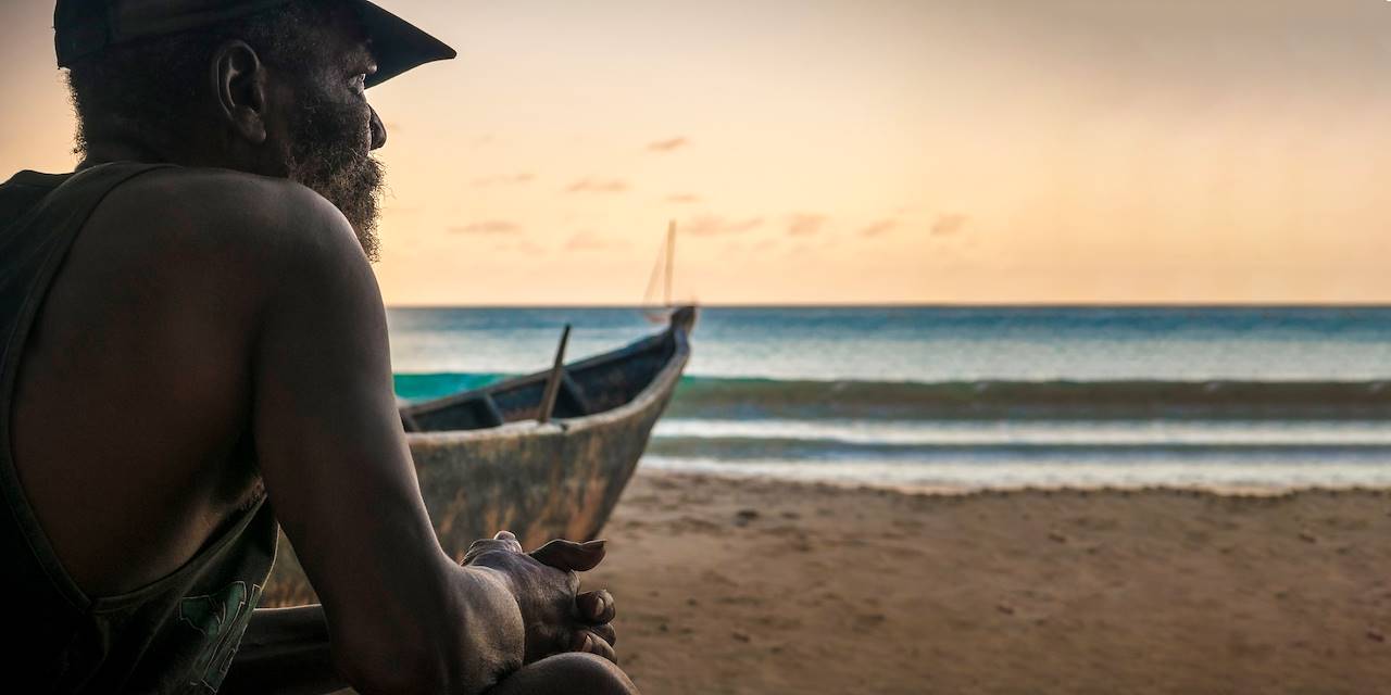 Pêcheur contemplant le coucher du soleil sur une plage de Mahé - Seychelles