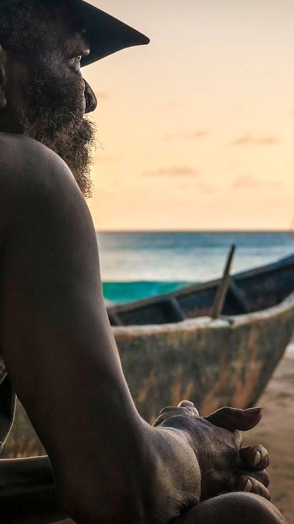 Pêcheur contemplant le coucher du soleil sur une plage de Mahé - Seychelles